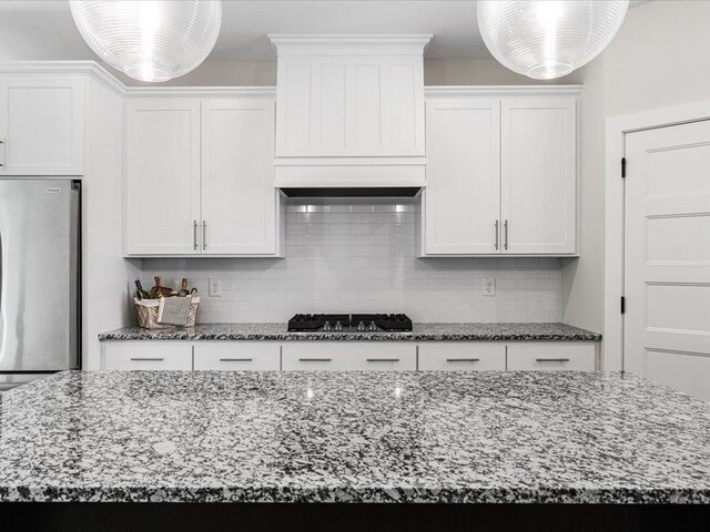 kitchen with appliances with stainless steel finishes, white cabinetry, decorative backsplash, and light stone counters