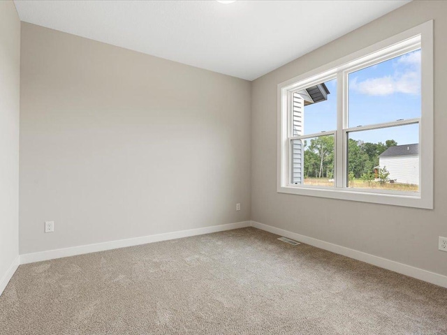 carpeted spare room featuring visible vents and baseboards