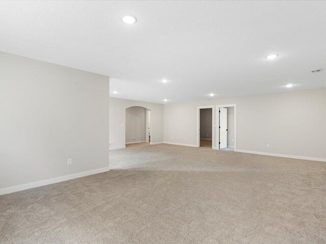 unfurnished room featuring arched walkways, baseboards, and recessed lighting