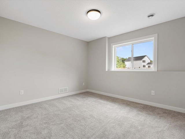 carpeted empty room featuring visible vents, baseboards, and a textured ceiling