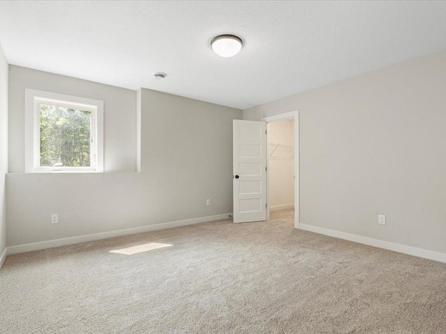 empty room with baseboards and light colored carpet