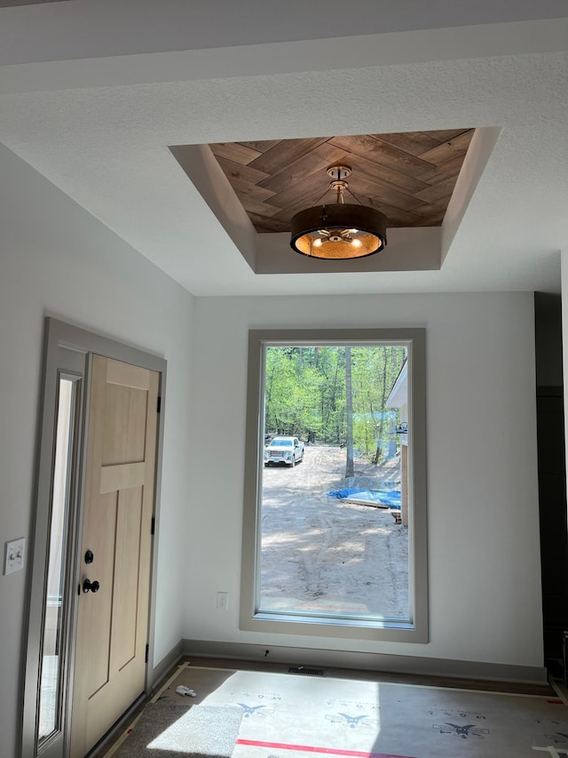 entryway featuring a raised ceiling and baseboards