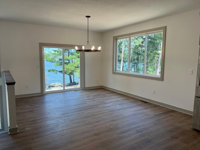 unfurnished dining area featuring a chandelier, healthy amount of natural light, dark wood finished floors, and baseboards