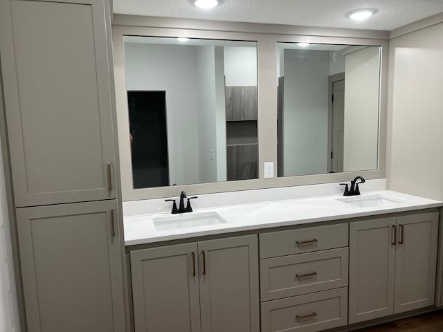 full bath featuring double vanity and a textured ceiling
