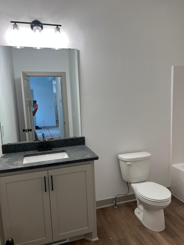 full bath with wood finished floors, baseboards, toilet, vanity, and a bathtub