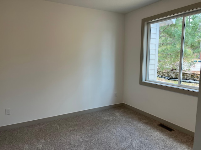 carpeted empty room featuring plenty of natural light and baseboards