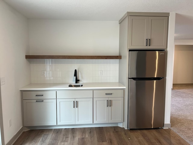kitchen featuring freestanding refrigerator, a sink, gray cabinetry, light countertops, and decorative backsplash
