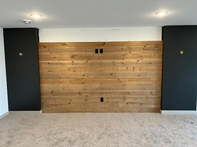 spare room featuring carpet flooring, a smoke detector, and wooden walls
