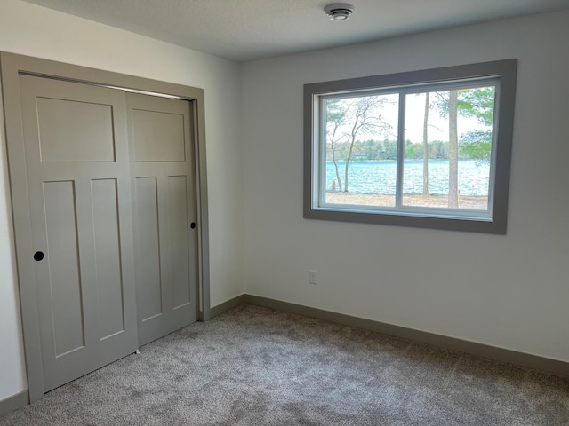 unfurnished bedroom featuring carpet flooring, baseboards, and a closet