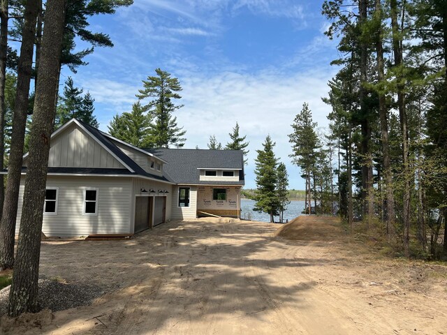 view of front facade with an attached garage, driveway, and a water view