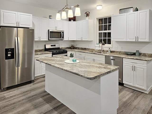 kitchen featuring stainless steel appliances, sink, decorative light fixtures, white cabinetry, and a kitchen island