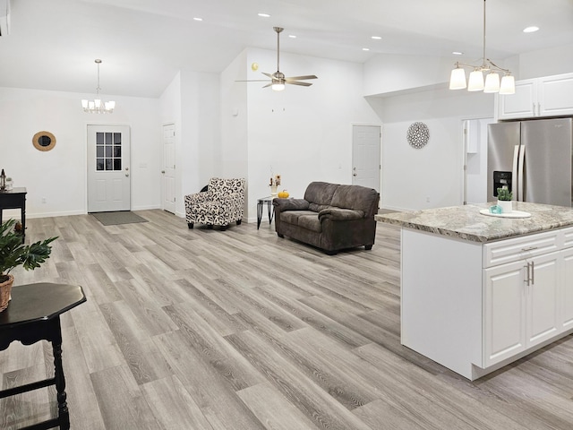 living room featuring ceiling fan with notable chandelier, light hardwood / wood-style floors, and lofted ceiling