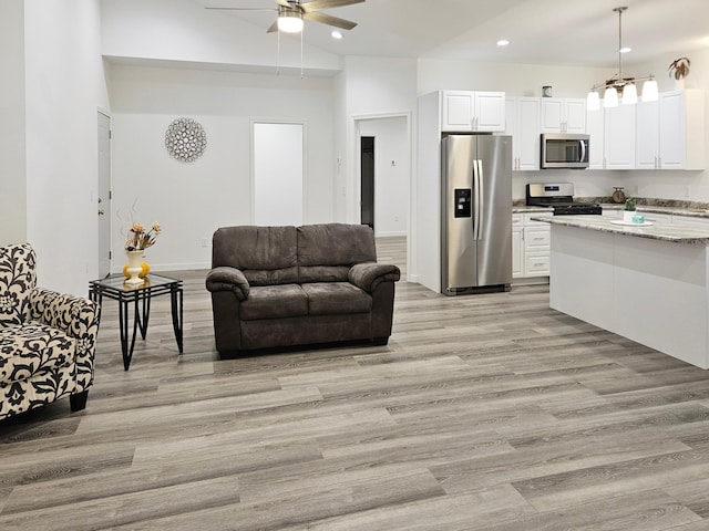 living room featuring ceiling fan, light hardwood / wood-style flooring, and high vaulted ceiling