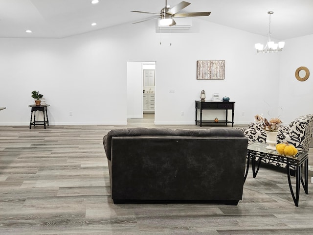 living room with ceiling fan with notable chandelier, high vaulted ceiling, and light hardwood / wood-style flooring