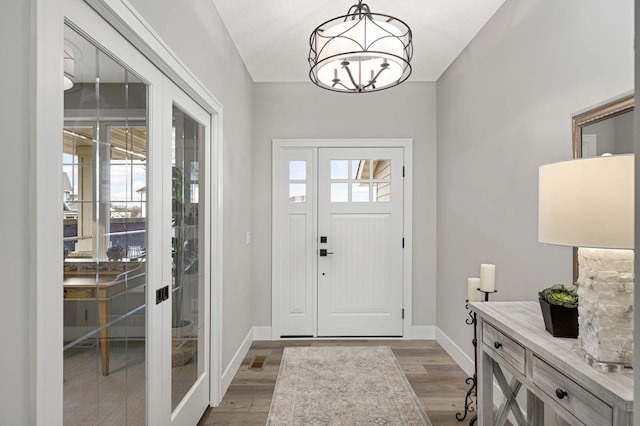 foyer with french doors, a chandelier, and light wood-type flooring