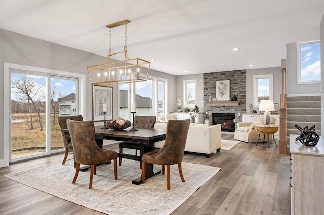 dining area with a fireplace, hardwood / wood-style floors, and a chandelier