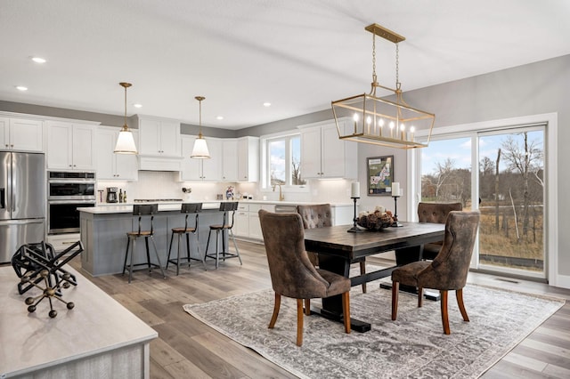 dining space featuring a wealth of natural light, sink, a notable chandelier, and light wood-type flooring