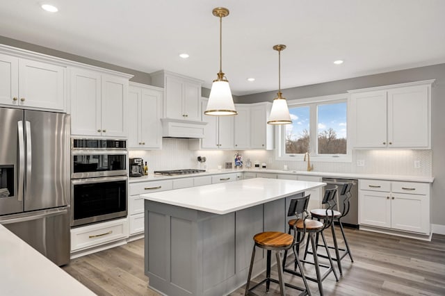 kitchen featuring white cabinets, appliances with stainless steel finishes, dark hardwood / wood-style flooring, and decorative light fixtures