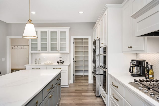 kitchen with gray cabinetry, white cabinets, light hardwood / wood-style flooring, tasteful backsplash, and decorative light fixtures