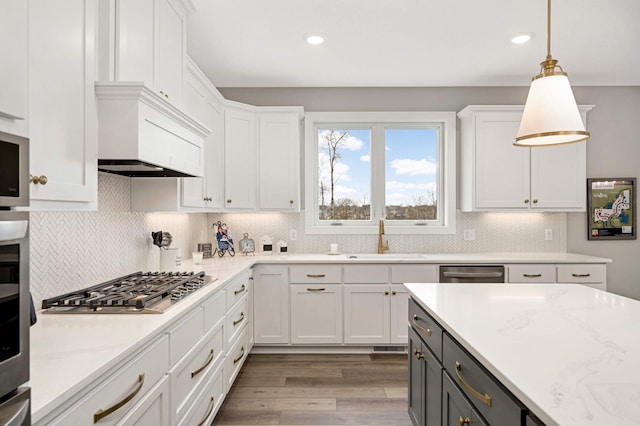 kitchen featuring white cabinets, sink, hanging light fixtures, light hardwood / wood-style flooring, and appliances with stainless steel finishes