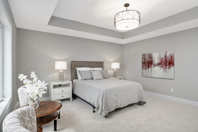 carpeted bedroom featuring a tray ceiling and multiple windows