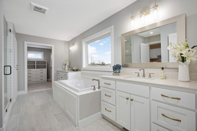 bathroom with a textured ceiling, vanity, and independent shower and bath