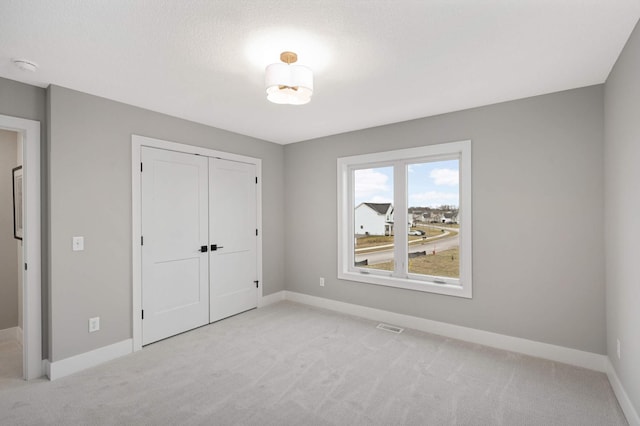 unfurnished bedroom featuring light carpet, a textured ceiling, and a closet