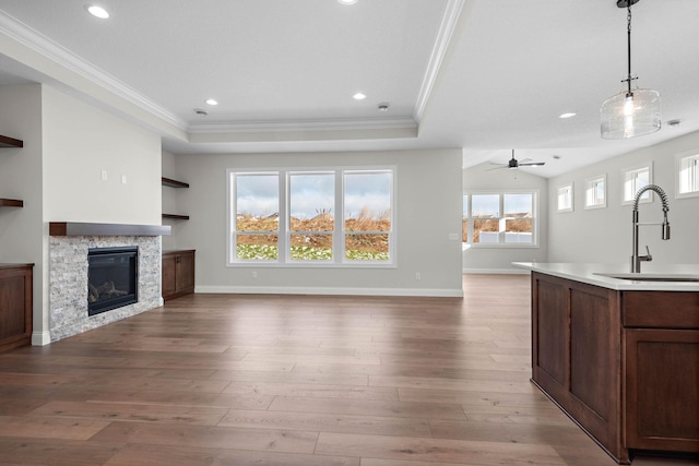 interior space featuring ornamental molding, sink, pendant lighting, a fireplace, and light hardwood / wood-style floors