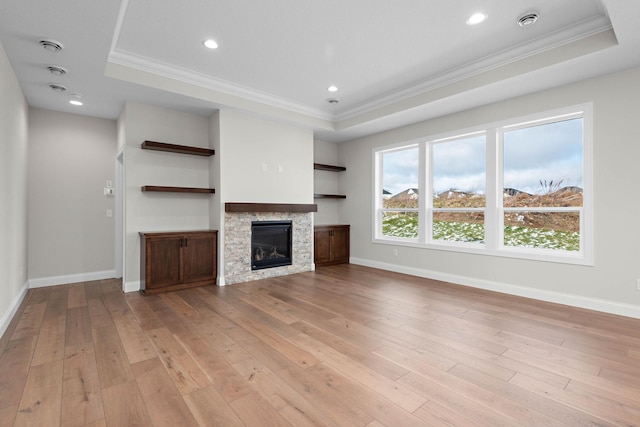 unfurnished living room with a fireplace, light wood-type flooring, a raised ceiling, and ornamental molding