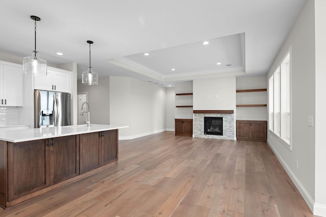 kitchen with a raised ceiling, a fireplace, stainless steel fridge, and light hardwood / wood-style flooring