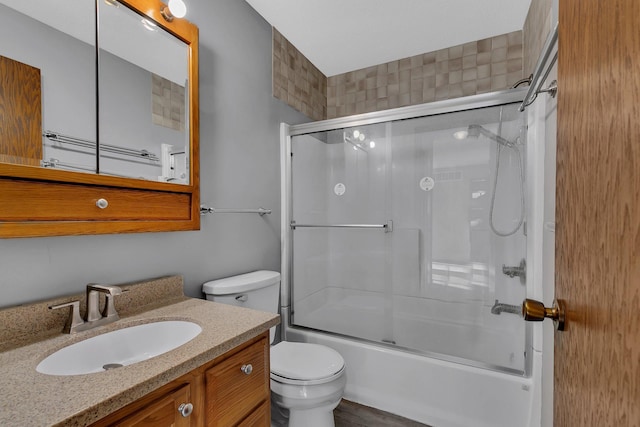 full bathroom with combined bath / shower with glass door, vanity, and toilet