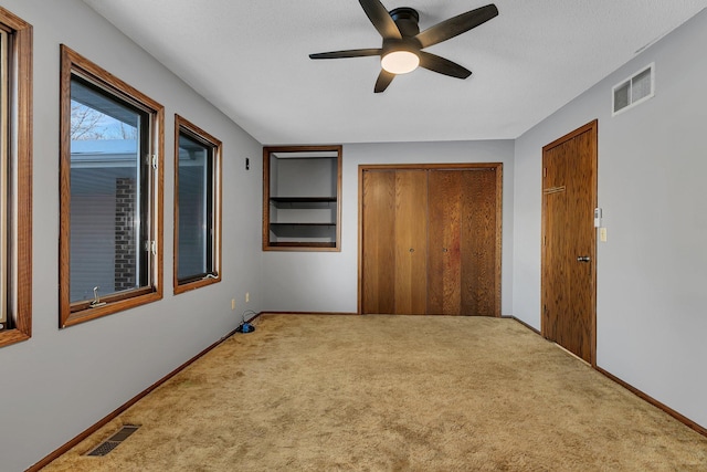 unfurnished bedroom featuring ceiling fan, two closets, and carpet floors