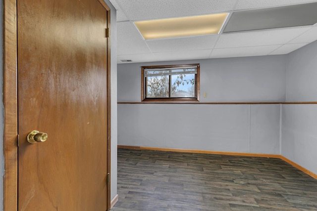 empty room featuring dark wood-type flooring and a drop ceiling