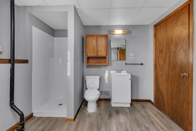 bathroom with a paneled ceiling, vanity, a shower, toilet, and hardwood / wood-style flooring