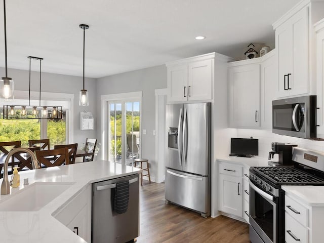 kitchen with hanging light fixtures, dark hardwood / wood-style flooring, white cabinetry, appliances with stainless steel finishes, and sink