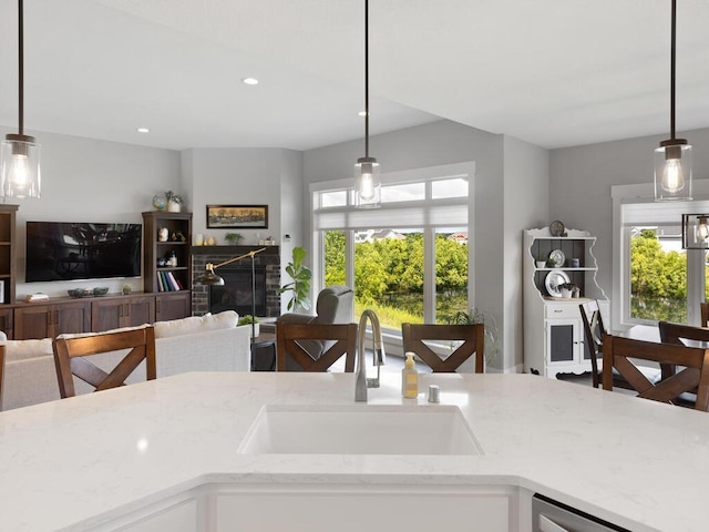 kitchen featuring sink, white cabinetry, pendant lighting, and light stone countertops