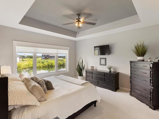 bedroom with ceiling fan, carpet, and a tray ceiling