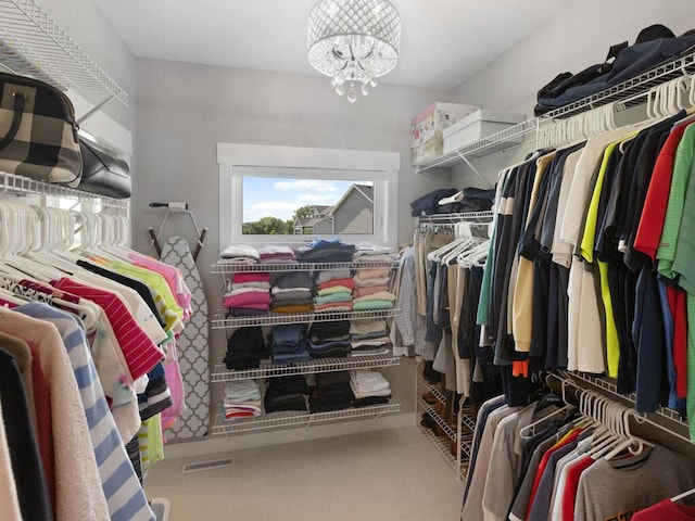 spacious closet with a notable chandelier and carpet flooring