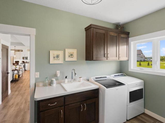 laundry room with sink, light hardwood / wood-style floors, cabinets, and independent washer and dryer