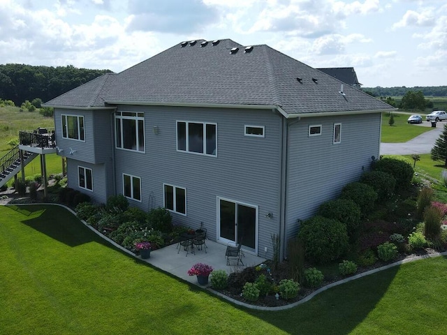 back of property with a patio area, a wooden deck, and a yard