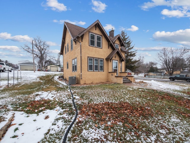 view of snow covered exterior featuring a garage, cooling unit, and an outdoor structure