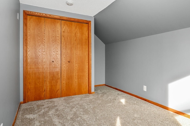 unfurnished bedroom featuring carpet, a closet, and lofted ceiling