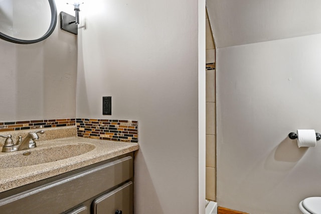 bathroom with toilet, vanity, and tasteful backsplash