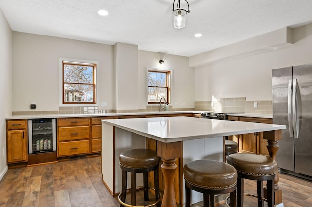 kitchen with a center island, stainless steel refrigerator, a breakfast bar area, and wine cooler