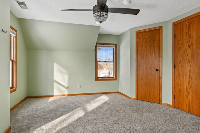 interior space featuring vaulted ceiling, ceiling fan, carpet floors, and a textured ceiling