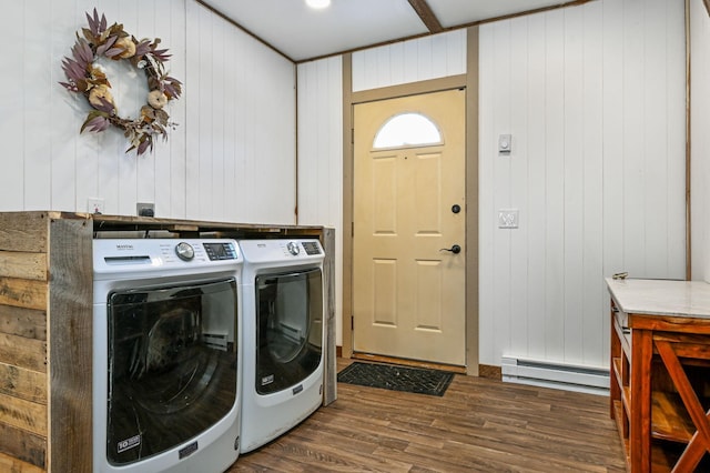 clothes washing area with a baseboard heating unit, washing machine and clothes dryer, and dark hardwood / wood-style flooring