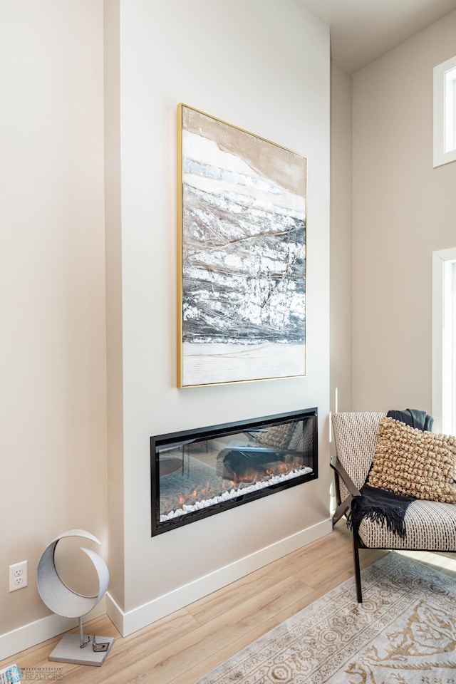131 Pine Ave, Mapleton, ND 58059 - living area featuring a glass covered fireplace, wood finished floors, and baseboards