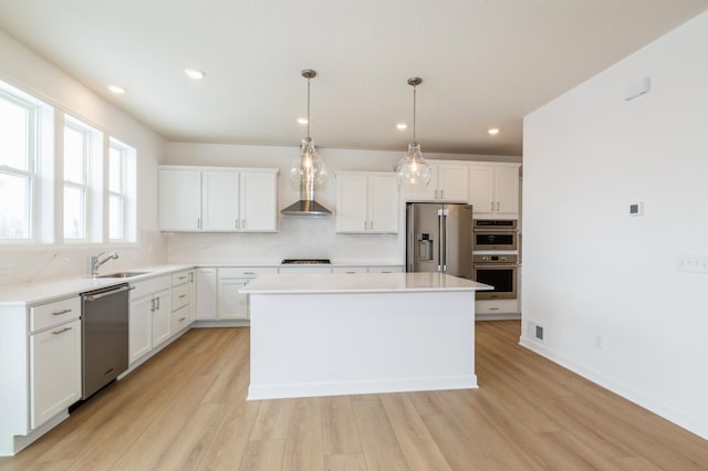 kitchen with sink, appliances with stainless steel finishes, a kitchen island, pendant lighting, and white cabinets