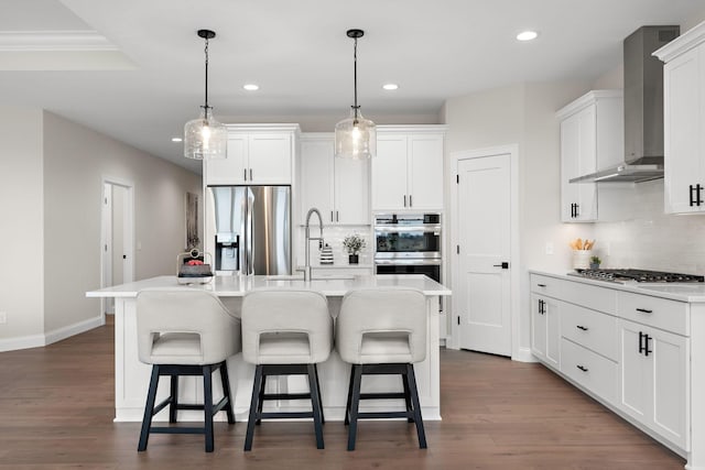 kitchen with white cabinetry, a kitchen island with sink, stainless steel appliances, and wall chimney range hood