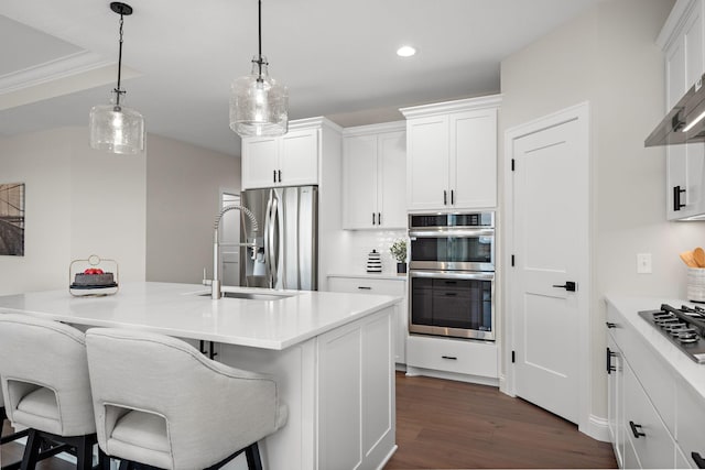 kitchen with sink, stainless steel appliances, dark hardwood / wood-style floors, a breakfast bar area, and white cabinets